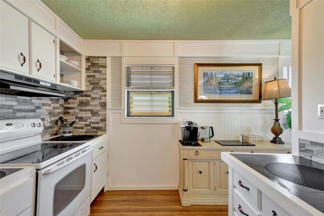 1805 15th St SW, Vero Beach, FL 32962 - kitchen with a textured ceiling, under cabinet range hood, white cabinetry, white range with electric cooktop, and backsplash