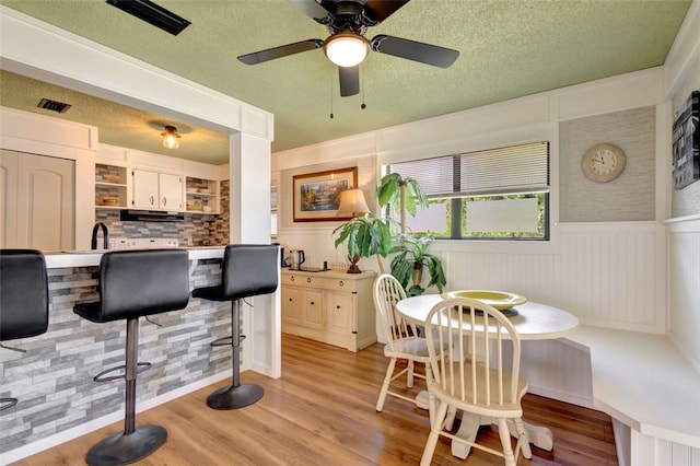 1805 15th St SW, Vero Beach, FL 32962 - dining area with a ceiling fan, a textured ceiling, visible vents, a wainscoted wall, and light wood-type flooring