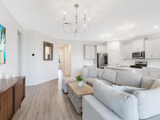 living area with an inviting chandelier, light wood-style flooring, visible vents, and recessed lighting