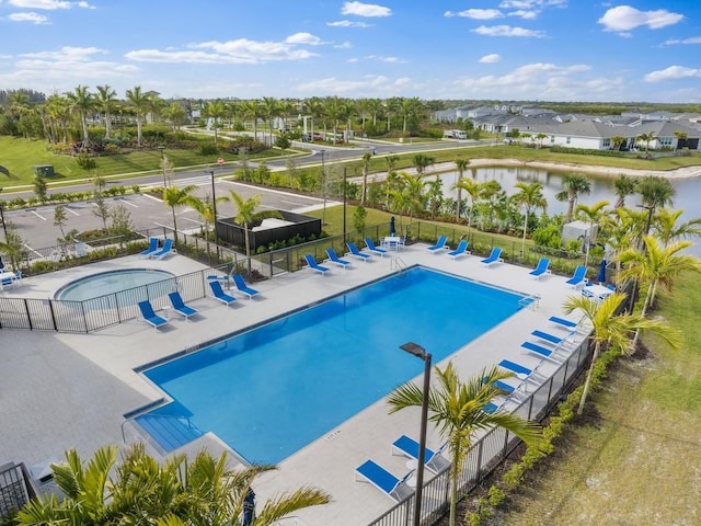 community pool featuring a patio area, a water view, fence, and a residential view