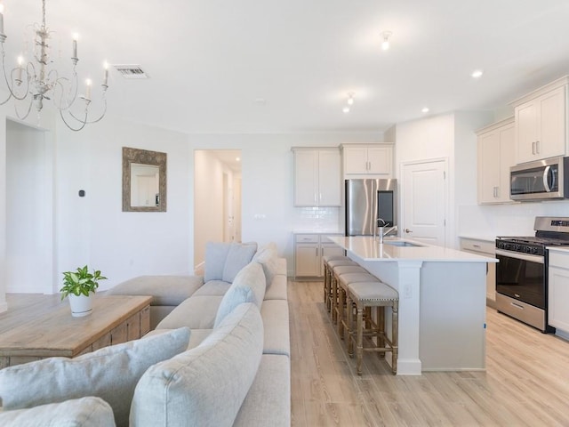 kitchen with visible vents, a kitchen breakfast bar, open floor plan, stainless steel appliances, and a sink