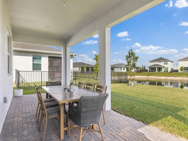 view of patio / terrace with a water view, a residential view, fence, and outdoor dining area