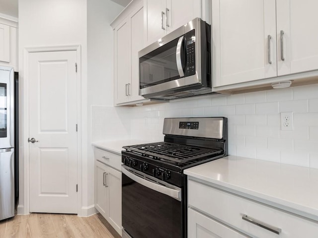 kitchen with stainless steel appliances, light countertops, decorative backsplash, white cabinets, and light wood-type flooring