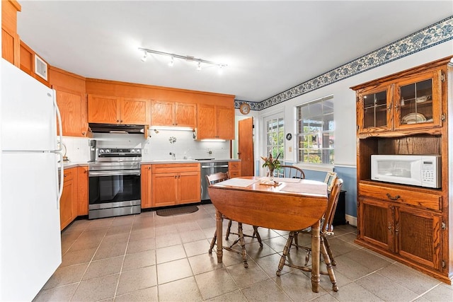 kitchen featuring backsplash, light tile patterned flooring, sink, and stainless steel appliances