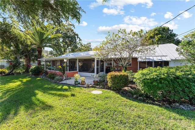 back of house featuring a lawn and a sunroom