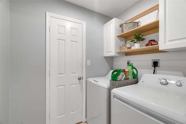 laundry room featuring separate washer and dryer and cabinets