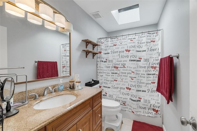 bathroom featuring vanity, toilet, a skylight, and tile patterned flooring