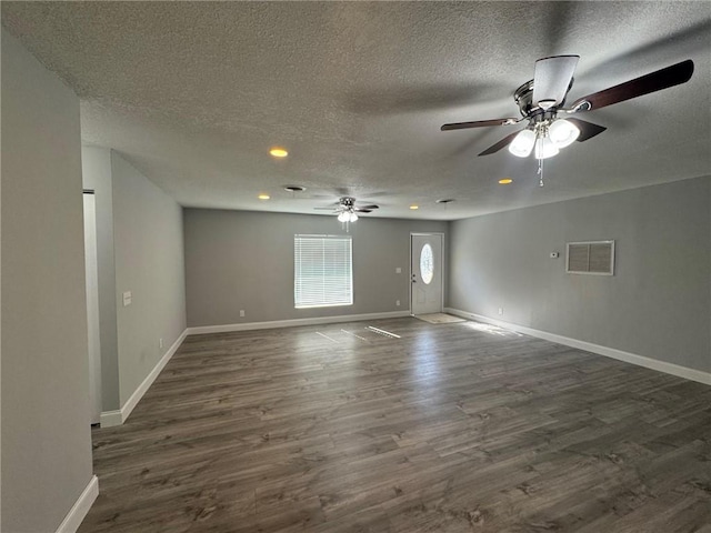 empty room featuring a ceiling fan, baseboards, visible vents, dark wood-style flooring, and a textured ceiling