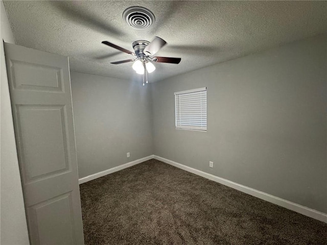 spare room featuring visible vents, baseboards, and dark carpet