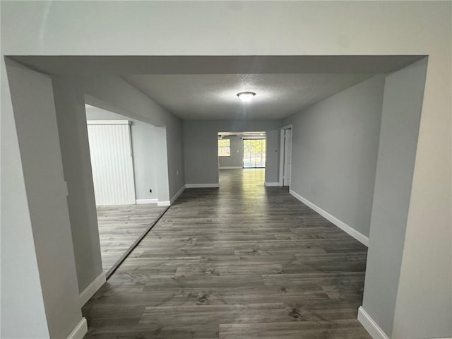 hall with baseboards, dark wood-style flooring, and a textured ceiling