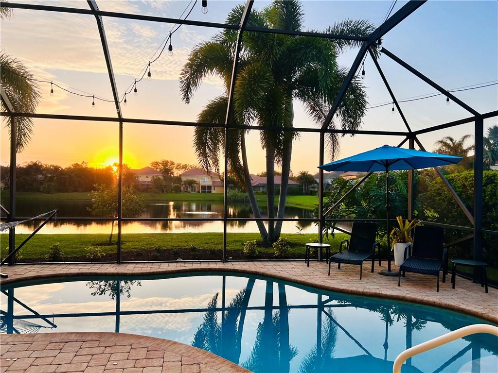 outdoor pool with a lanai, a patio area, and a water view