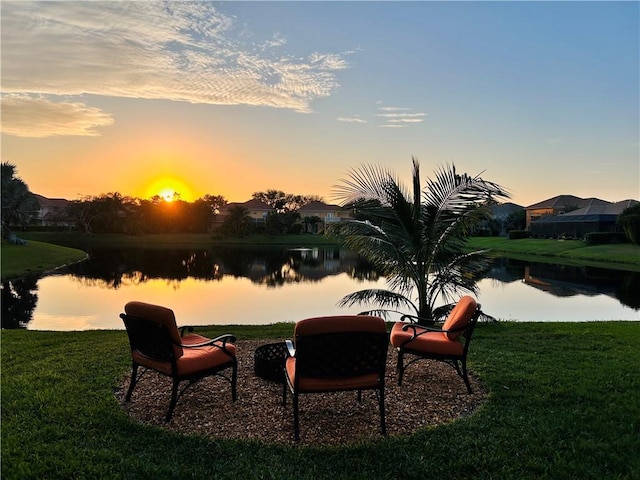 surrounding community with a water view and a lawn