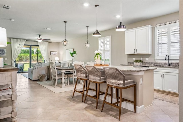5151 Jasper Sq, Vero Beach, FL 32967 - kitchen with a sink, open floor plan, light stone counters, a ceiling fan, and white cabinets