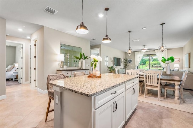 5151 Jasper Sq, Vero Beach, FL 32967 - kitchen featuring a center island, white cabinetry, hanging light fixtures, light stone countertops, and recessed lighting