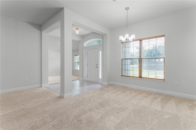 carpeted entryway with a chandelier