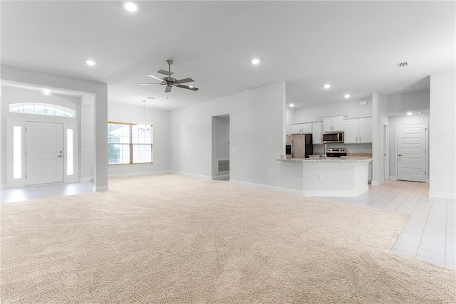 unfurnished living room featuring ceiling fan with notable chandelier and light tile patterned flooring