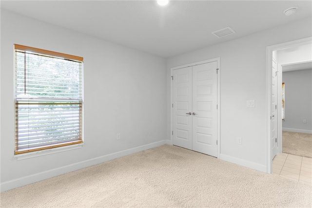 unfurnished bedroom featuring light colored carpet and a closet