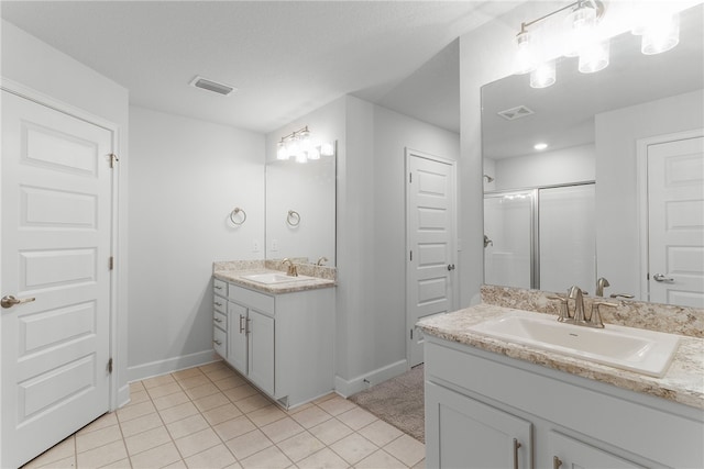 bathroom featuring vanity, a shower with shower door, and tile patterned floors