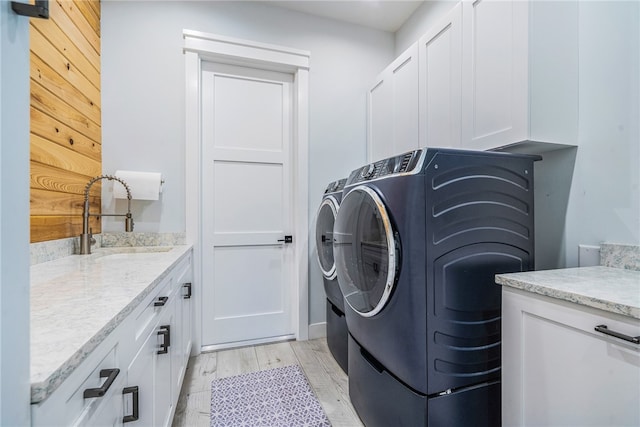 laundry room with cabinets, light hardwood / wood-style floors, sink, and independent washer and dryer