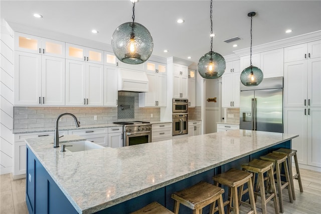 kitchen featuring white cabinets, premium appliances, sink, and a large island