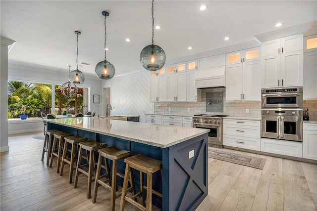 kitchen with a spacious island, hanging light fixtures, light stone counters, and stainless steel appliances