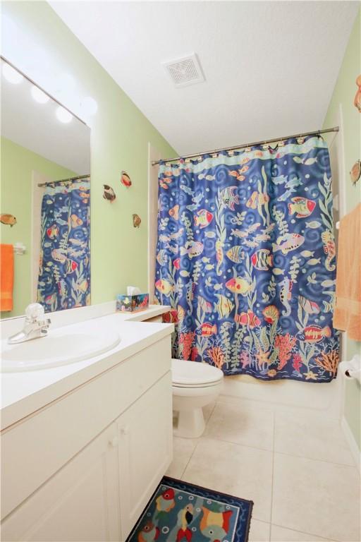 bathroom with tile patterned flooring, vanity, toilet, and a shower with curtain