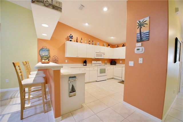 kitchen featuring kitchen peninsula, vaulted ceiling, white appliances, a breakfast bar area, and white cabinets