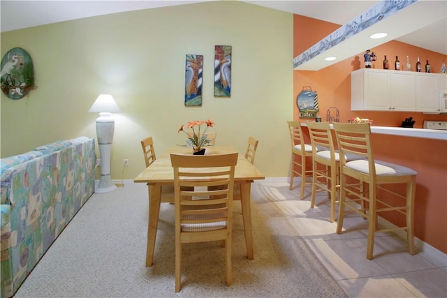 dining space featuring light carpet and vaulted ceiling