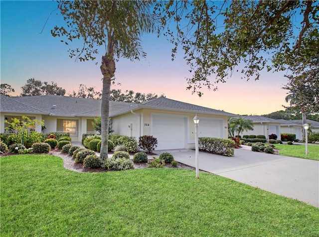 single story home featuring a garage and a lawn