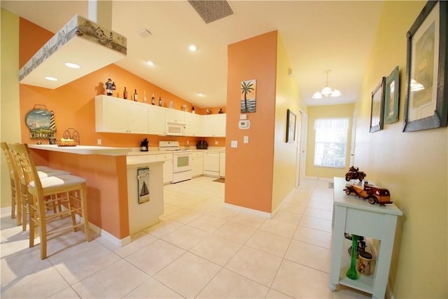 kitchen featuring lofted ceiling, white appliances, white cabinets, a kitchen bar, and kitchen peninsula