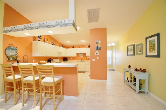 kitchen with white cabinetry, sink, a kitchen breakfast bar, kitchen peninsula, and white appliances