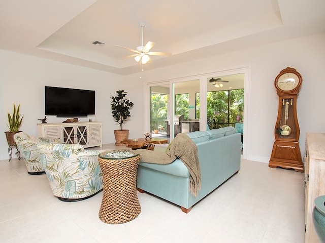 living room featuring ceiling fan and a raised ceiling