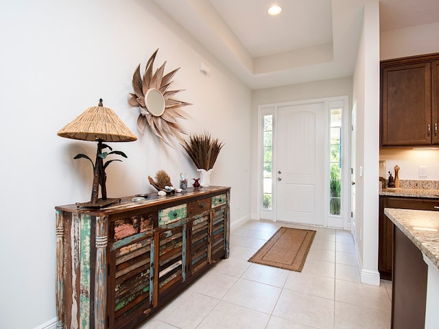 foyer entrance featuring a tray ceiling and light tile patterned floors