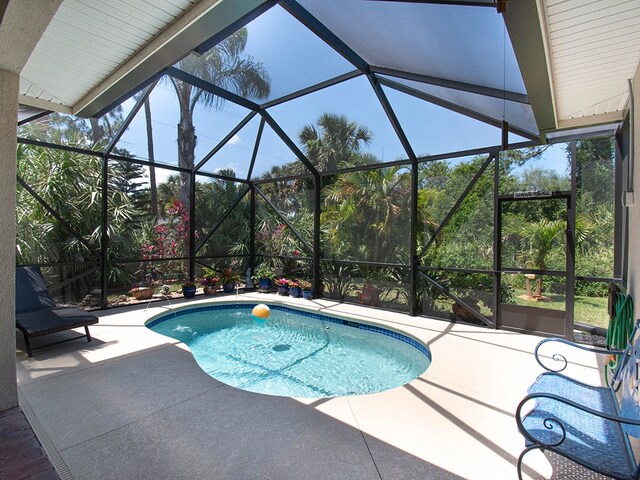 view of pool with glass enclosure and a patio area