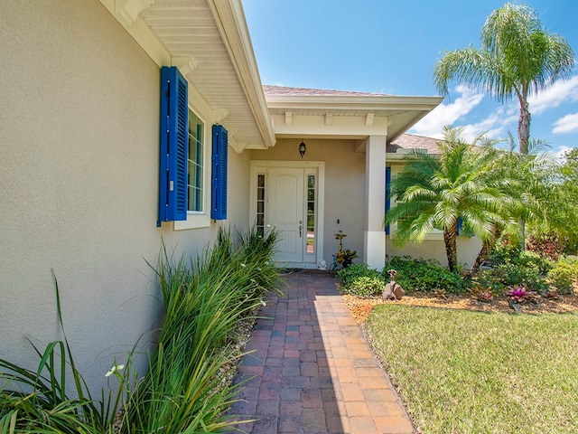 view of exterior entry featuring a lawn