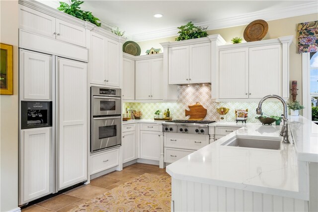 kitchen featuring white cabinets, decorative backsplash, sink, crown molding, and appliances with stainless steel finishes