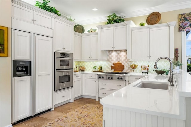 410 N Palm Island Cir, Vero Beach, FL 32963 - kitchen featuring appliances with stainless steel finishes, decorative backsplash, a peninsula, white cabinetry, and crown molding