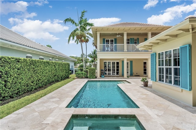 rear view of property with french doors, a patio, a swimming pool with hot tub, ceiling fan, and a balcony