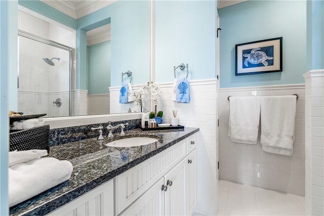 bathroom with ornamental molding, tile walls, vanity, and a shower with shower door