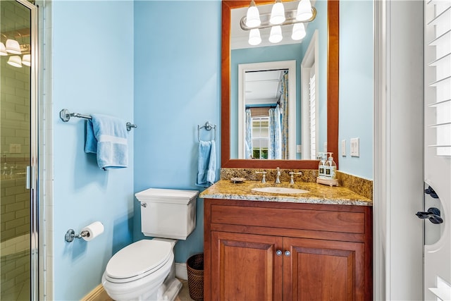 bathroom featuring toilet, vanity, and a shower with shower door