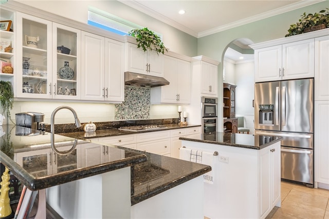 kitchen featuring white cabinetry, stainless steel appliances, a center island, and dark stone countertops