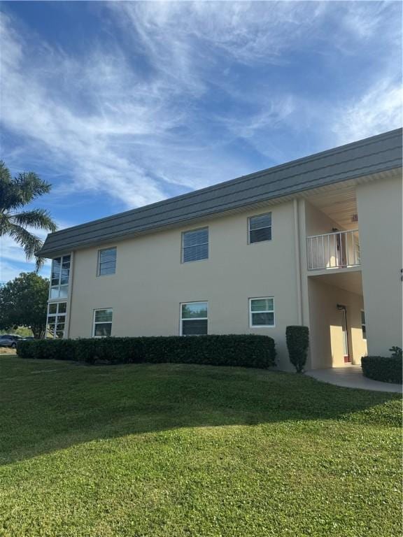 view of side of home featuring a lawn and a balcony