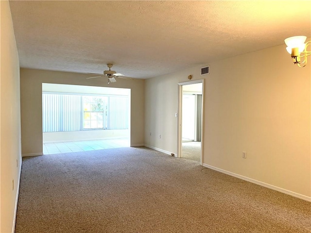 carpeted empty room with ceiling fan with notable chandelier and a textured ceiling