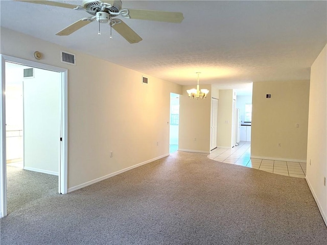 unfurnished room featuring ceiling fan with notable chandelier, light colored carpet, and a textured ceiling