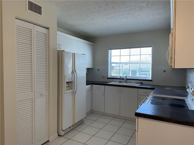 kitchen featuring sink, backsplash, white cabinets, light tile patterned floors, and white appliances