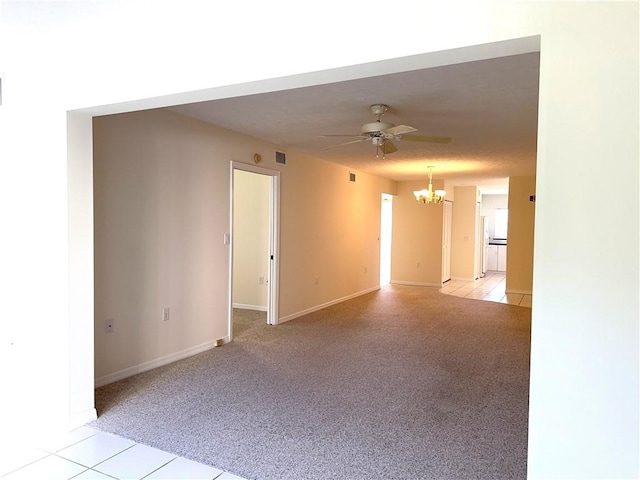 carpeted spare room with ceiling fan with notable chandelier