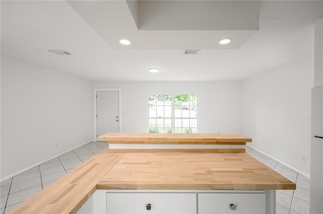 2313 2nd St SW, Vero Beach, FL 32962 - kitchen with light tile patterned floors, white cabinets, recessed lighting, butcher block counters, and freestanding refrigerator