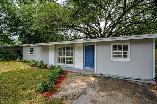 2313 2nd St SW, Vero Beach, FL 32962 - view of front of home with a front yard, a patio, and brick siding
