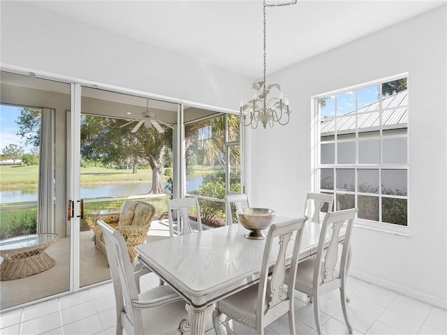 dining area with light tile patterned floors, ceiling fan with notable chandelier, and a water view