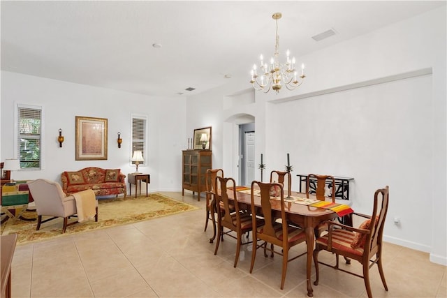 dining area featuring arched walkways, light tile patterned floors, a chandelier, and baseboards